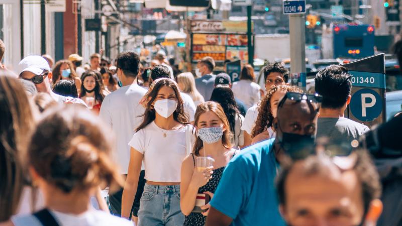 Persone che camminano per strada indossando la mascherina.