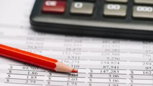 matita rossa e calcolatrice sopra un rapporto finanziario